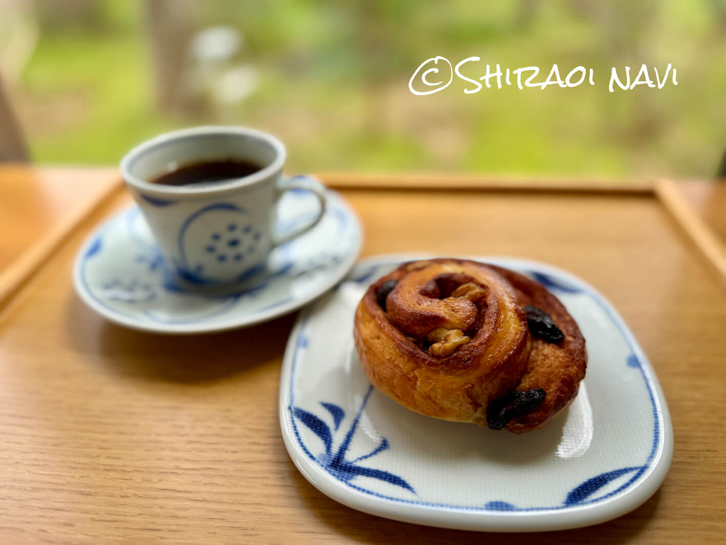 白老町のカフェ・カレンデュラのシナモンロールセット。香ばしく焼き上げたシナモンロールにドリンクが添えられ、森の景色を眺めながらゆったり楽しめるカフェタイム。
