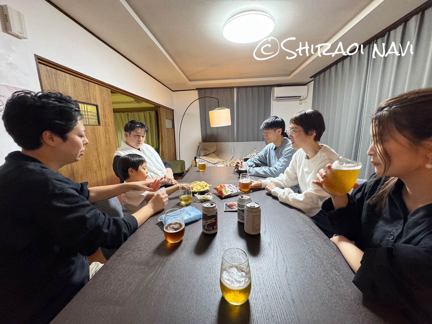 白老の貸別荘「Shiraoi Villa Auty」で過ごす夜の時間。近くの飲食店で食事を楽しんだあと、宿に戻って“飲み直し”できるのも一棟貸しの魅力。大きなテーブルを囲みながら、グループでゆっくり過ごせる空間。